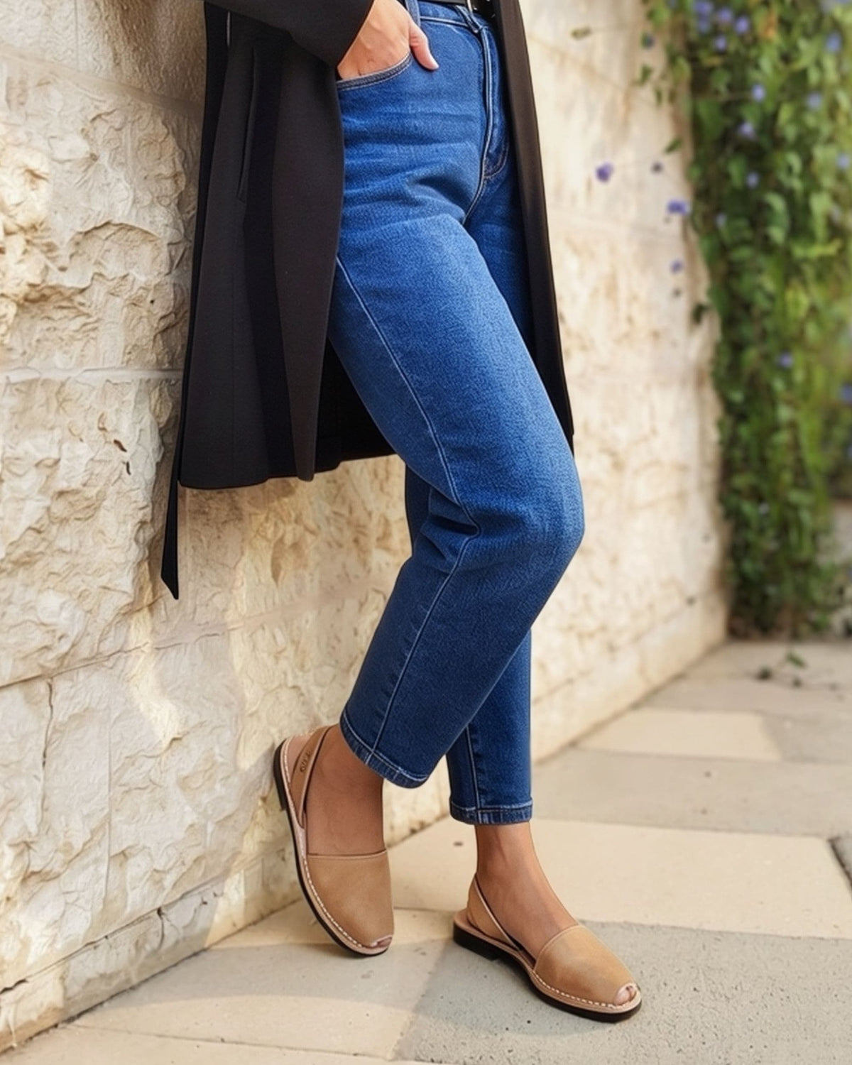 Tan leather flat sandals with secure slip-on heel strap, paired with blue jeans, made in Menorca | Classic Avarca by Shoeq