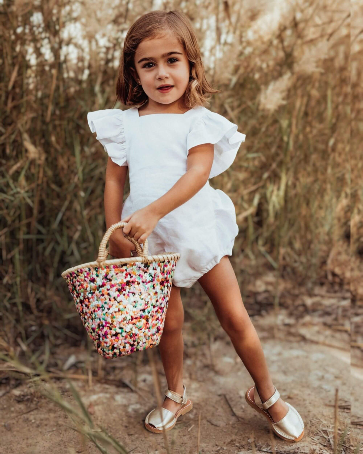 Champagne gold kids leather sandals with an ankle strap, worn with a white playsuit | Girls Ankle Strap Avarca by Shoeq
