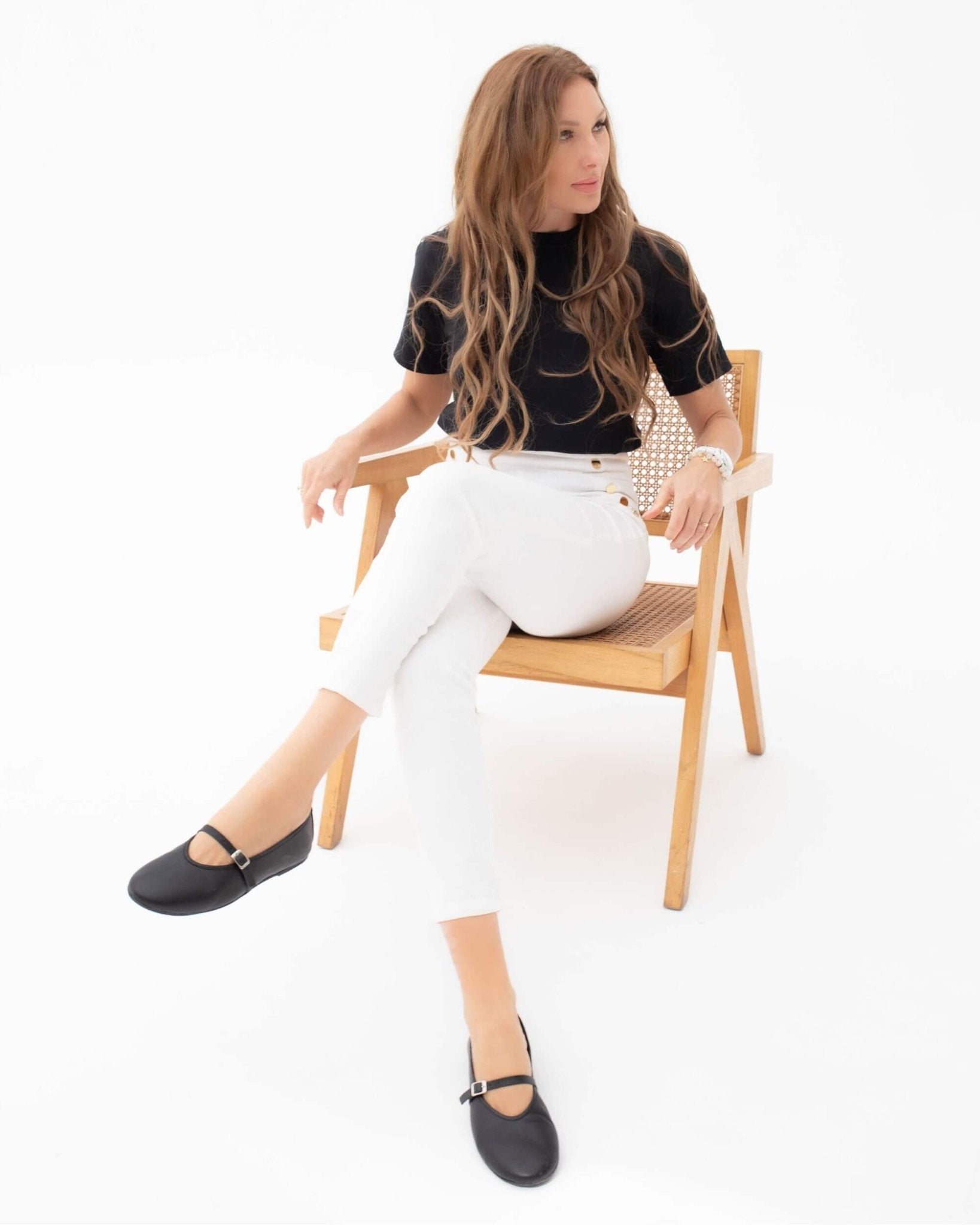 Handmade black nappa leather Mary Jane flats with closed toe worn seated, styled with white tailored trousers | Mary Jane in Midnight by Shoeq